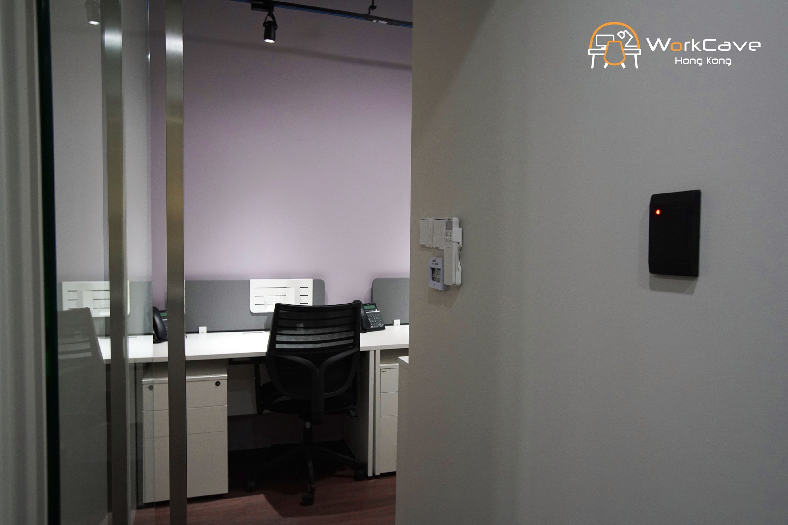 WorkCave 2-pax office, building view, tables and chairs facing purple wall, with hallway