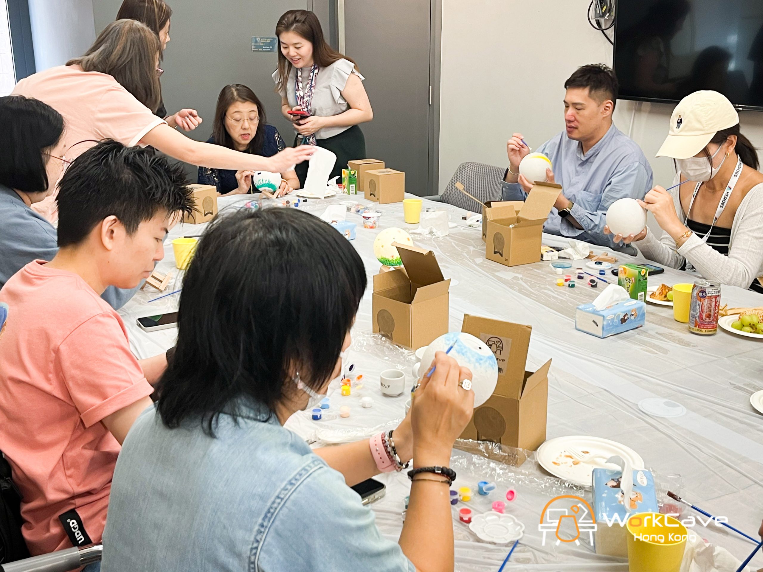 A close up to some workcavers using their brushes and painting their own moon lamps